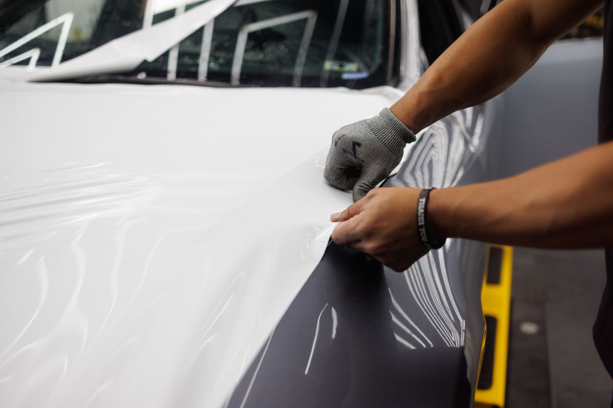 Close-up of vinyl wrap film being applied to a vehicle panel