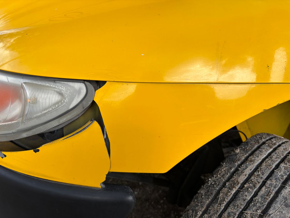 Before repair — visible dent and damage on a car bumper panel
